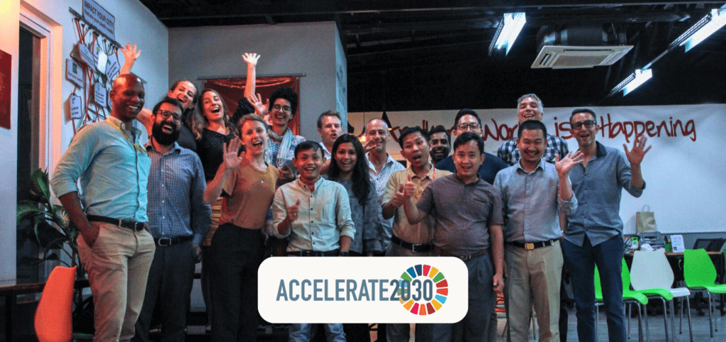 A group photo of around 20 smiling participants of Accelerate2030 Cambodia and members of the Impact Hub Phnom Penh staff inside an office.