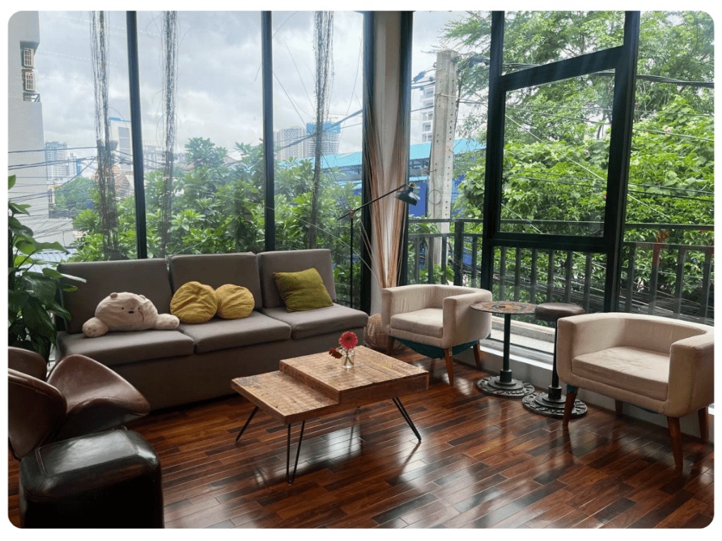 A photo of a corner of sofas in front of large windows in a corner of Impact Hub Phnom Penh's office.