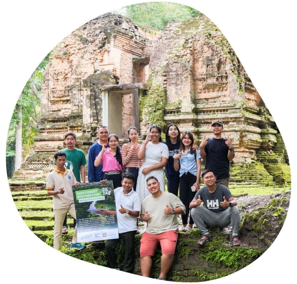 A group of entrepreneurs and Impact Hub Phnom Penh staff pose in front of a historic temple on a field trip with the SAFE Forest Restoration Incubation Program in Cambodia.