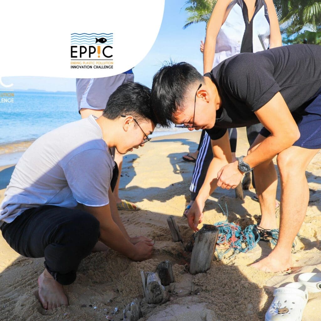 Two male push out the plastic from the sand next to the beach and few people helping there