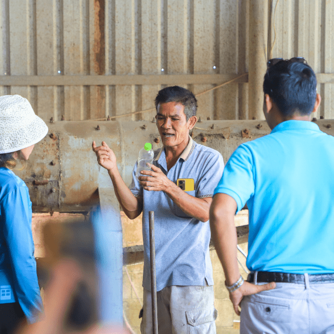 An uncle holding a plastic bottle explaining to our participant how the factory can recycle it