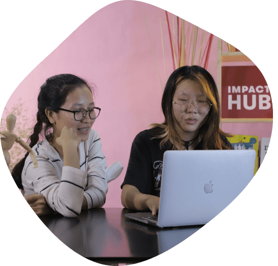 Two women sit at a computer together preparing to film an online course as part of the Changemakers Scale Up program