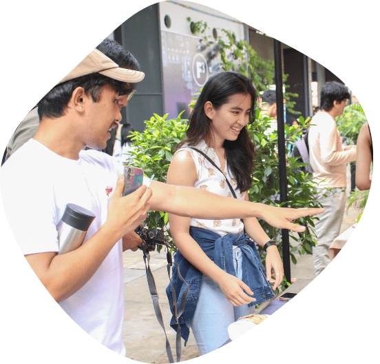 Two young people stand at a booth smiling and gesturing