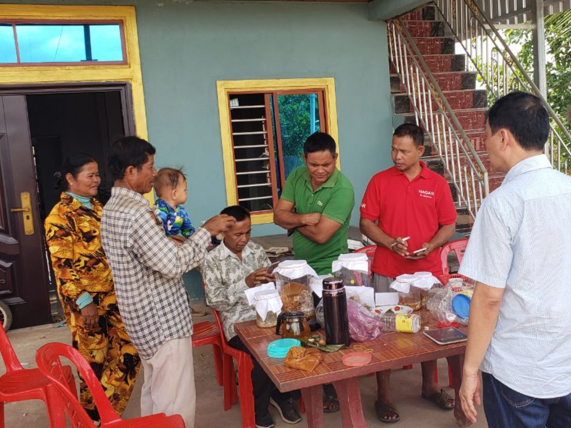 A group of farmers stand around a table in rural Cambodia preparing liquid compost.