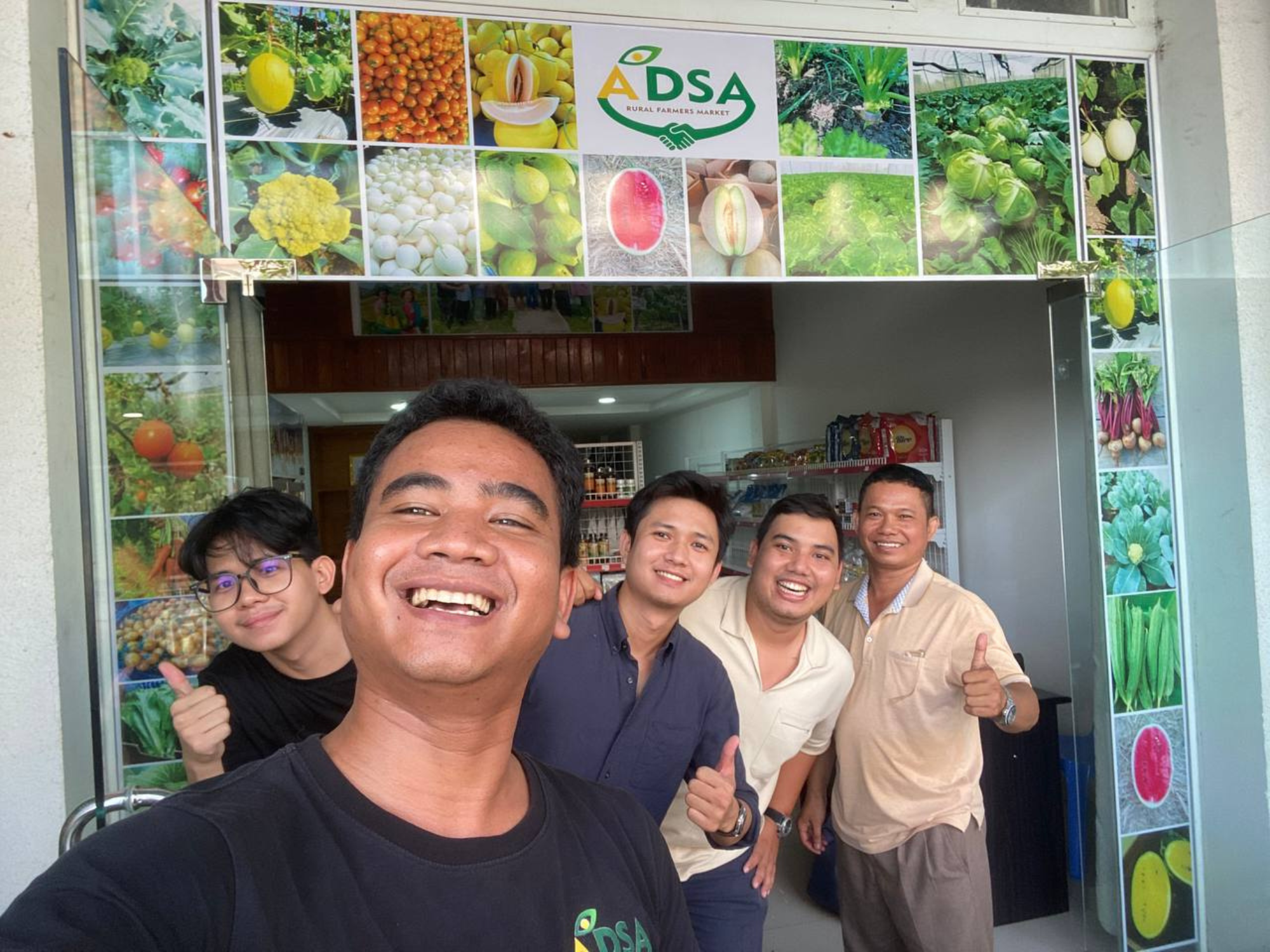 Two staff from ADSA smile and take a selfie with three members of the Impact Hub Phnom Penh team