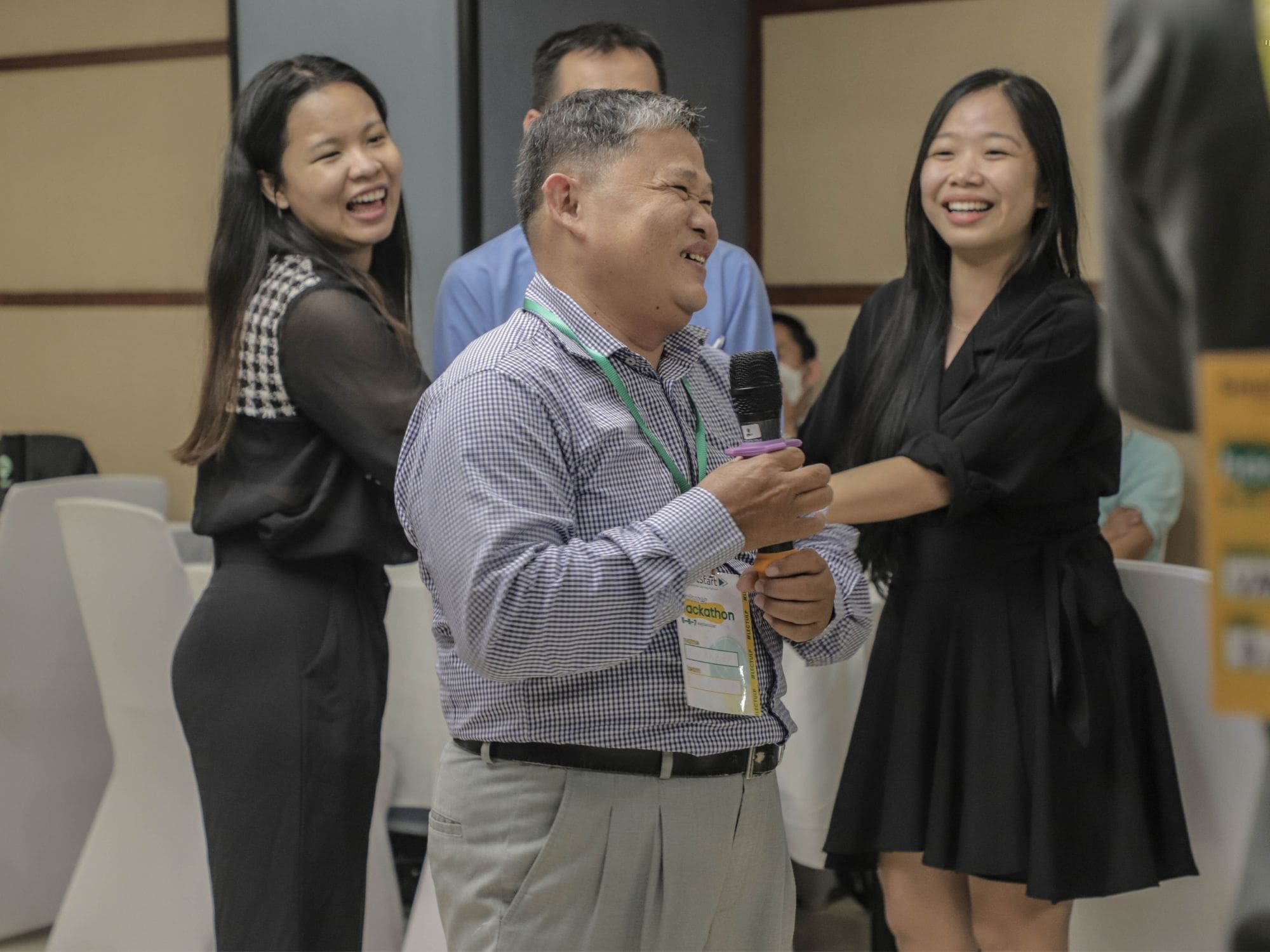 Four university professors stand and laugh with Impact Hub Phnom Penh staff during an interactive activity.