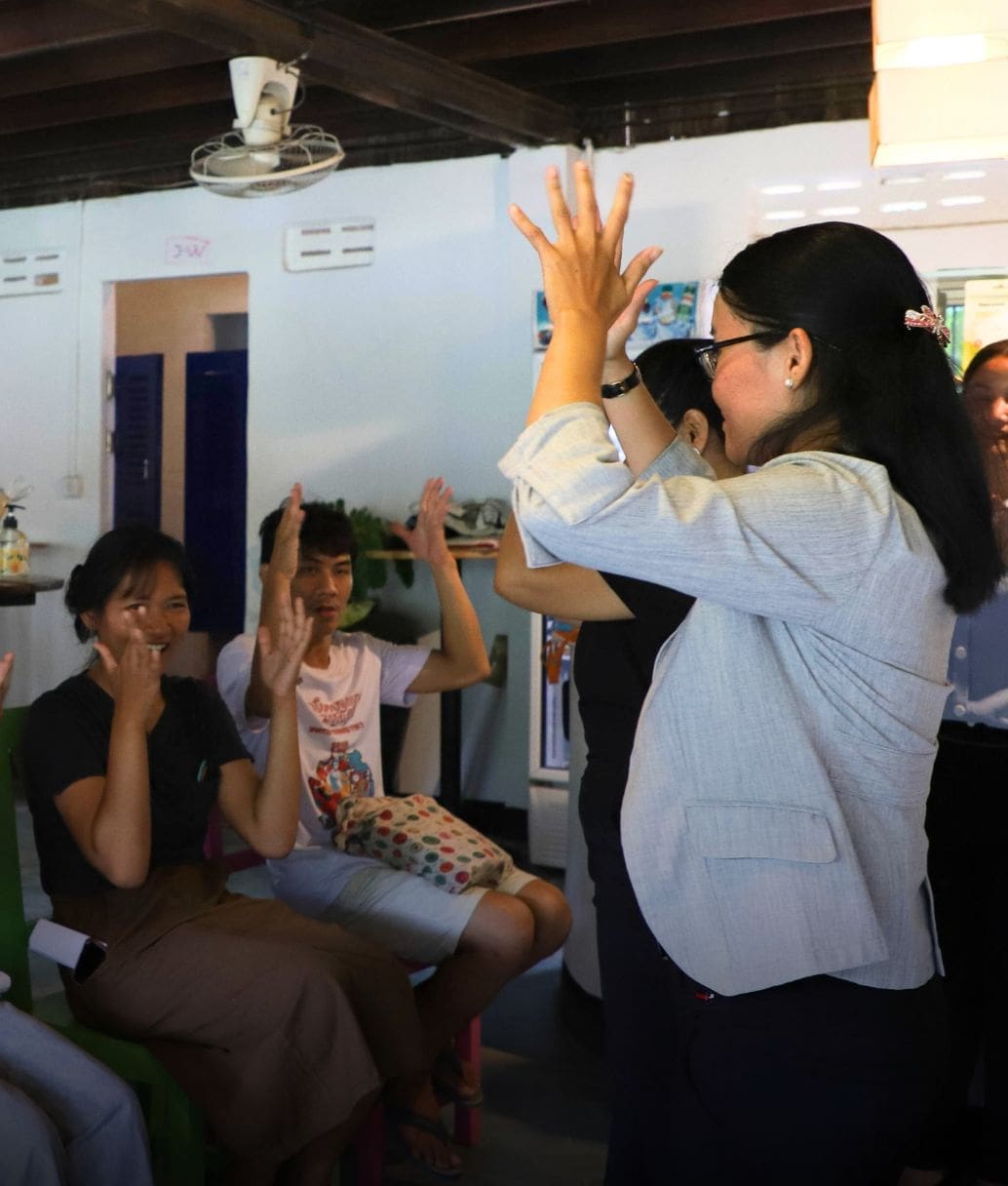 A group of people learning Cambodian Sign Language at an Impact Hub Phnom Penh workshop.