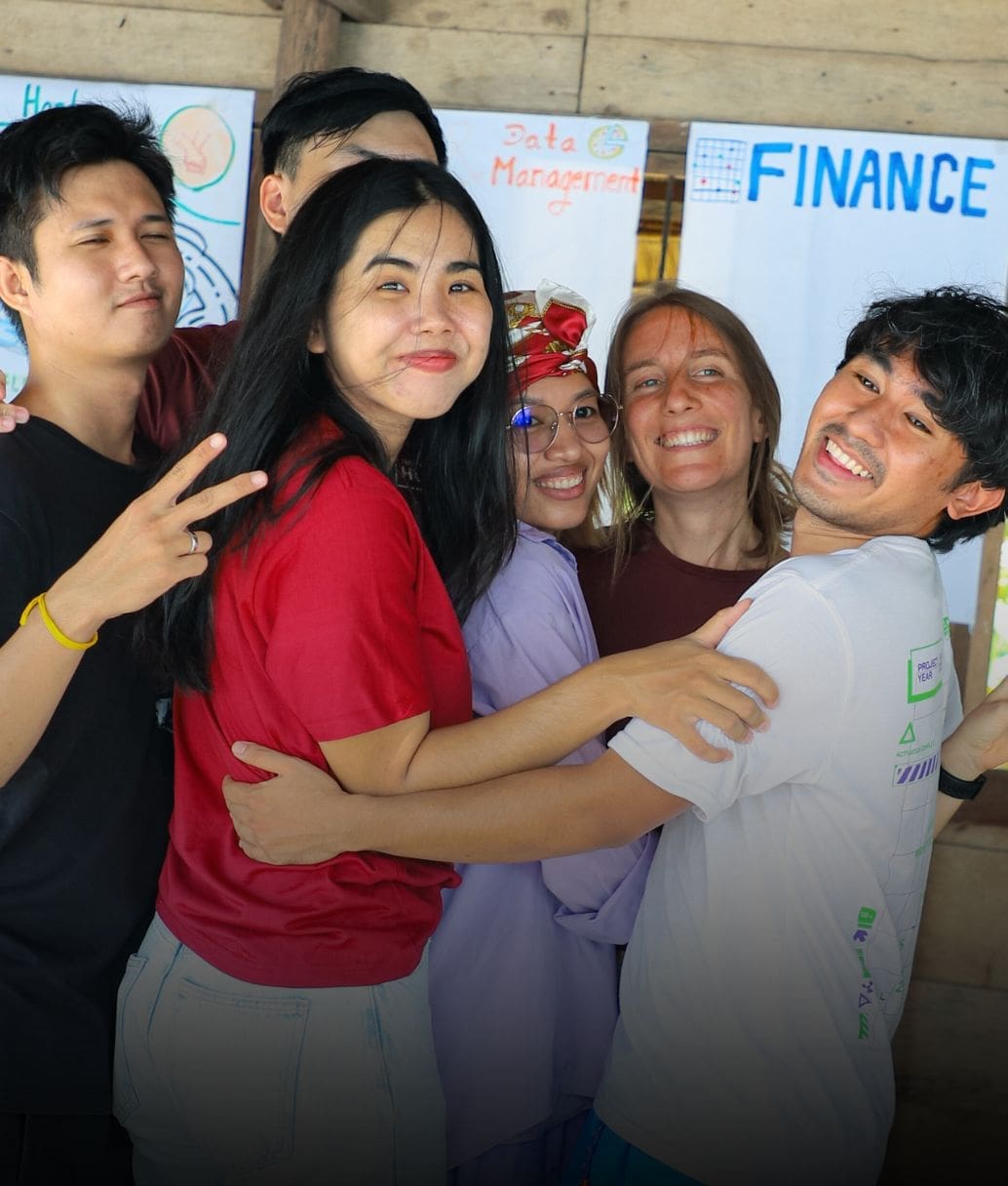 Six Impact Hub Phnom Penh staff laugh in a group hug as they look towards the camera.