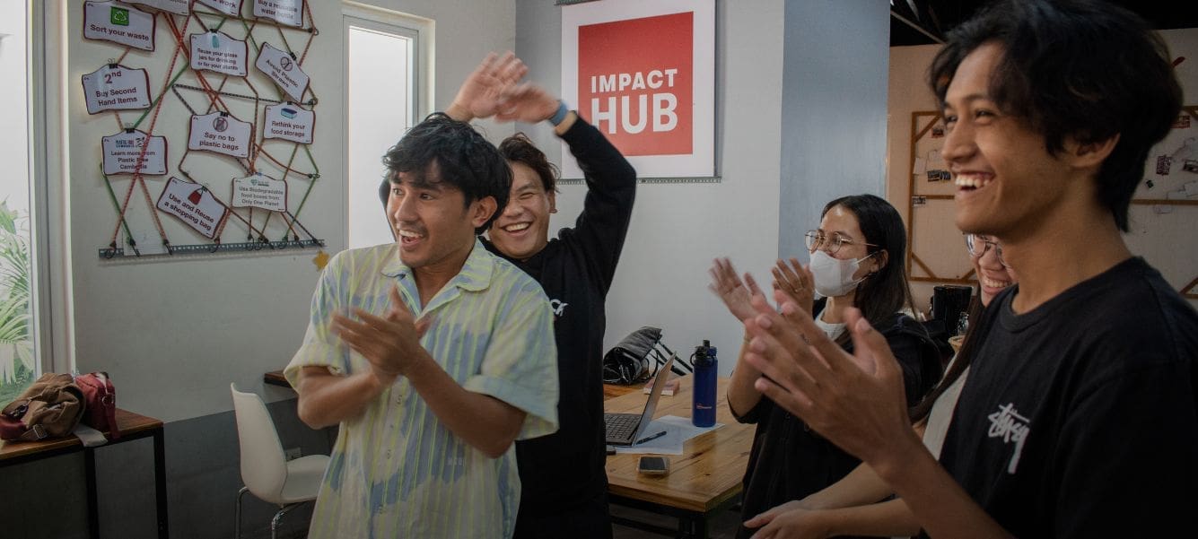 A handful of people stand clapping and cheering at the Impact Hub Phnom Penh offices.