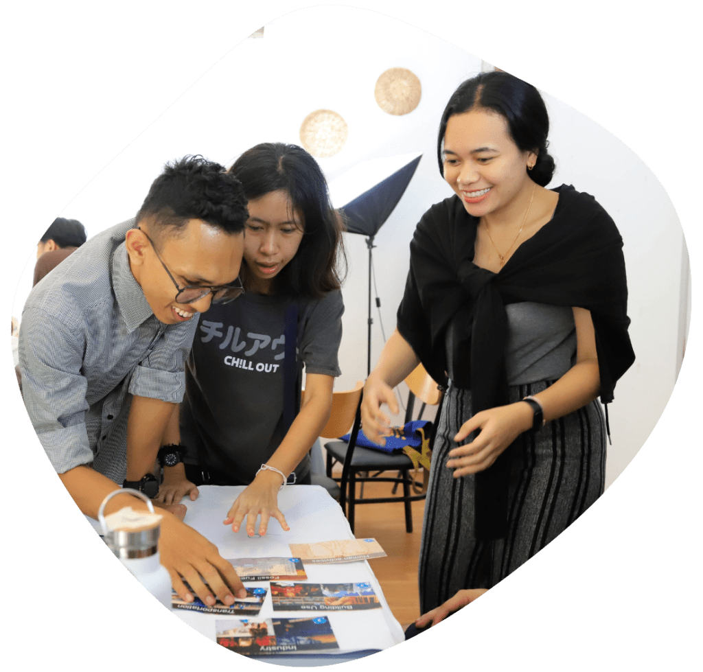 Three young Cambodians collaborate on an activity around a table while laughing.