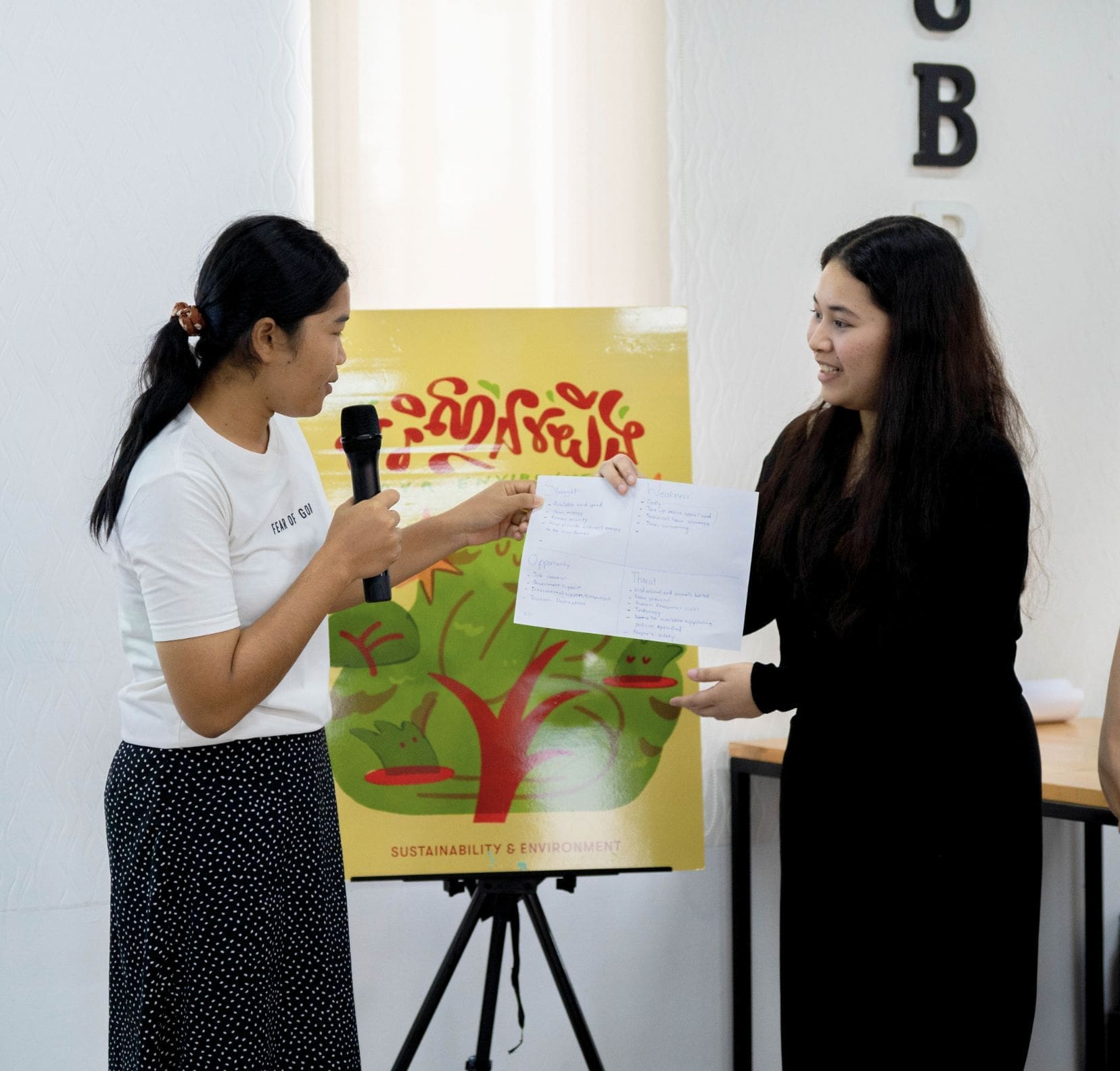 Two young Cambodian entrepreneurs collaborate and review work together.