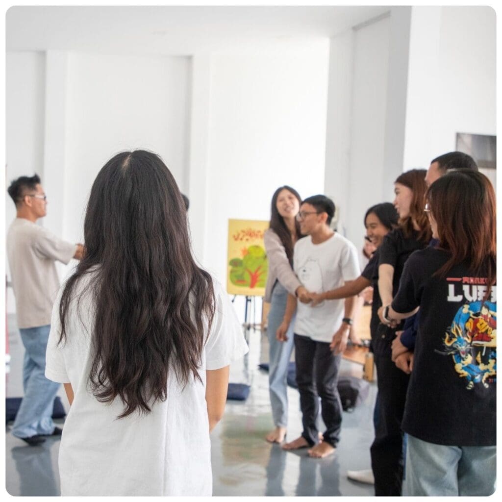 A group of young people stand and laugh as they do an icebreaker activity in Impact Hub Phnom Penh's event space.